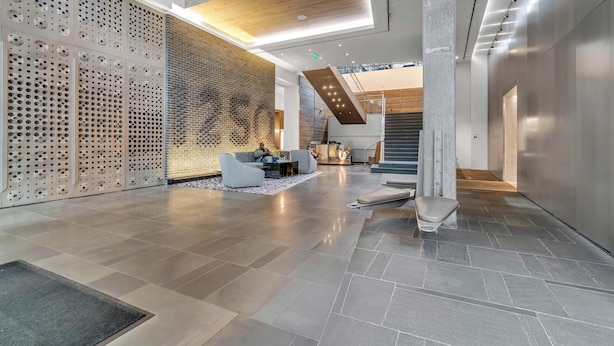 A spacious lobby with a high ceiling, a seating area, and a staircase leading to upper floors. - Fully Furnished Apartments near Nationals Park (Washington)