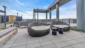 A rooftop patio with wicker furniture, string lights, and a view of the cityscape. - Fully Furnished Apartments near Nationals Park (Washington)