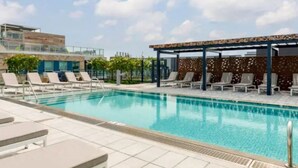 A pool area with lounge chairs and a covered seating area. - Fully Furnished Apartments near Nationals Park (Washington)