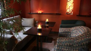 Un'accogliente zona con divano, una poltrona decorata e un tavolino con candele.