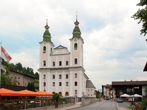 Eine große Kirche mit zwei Türmen und einer Uhr, umgeben von Gebäuden und einer Straße.