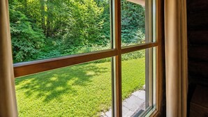 Une fenêtre donnant sur un paysage verdoyant et une structure en bois.