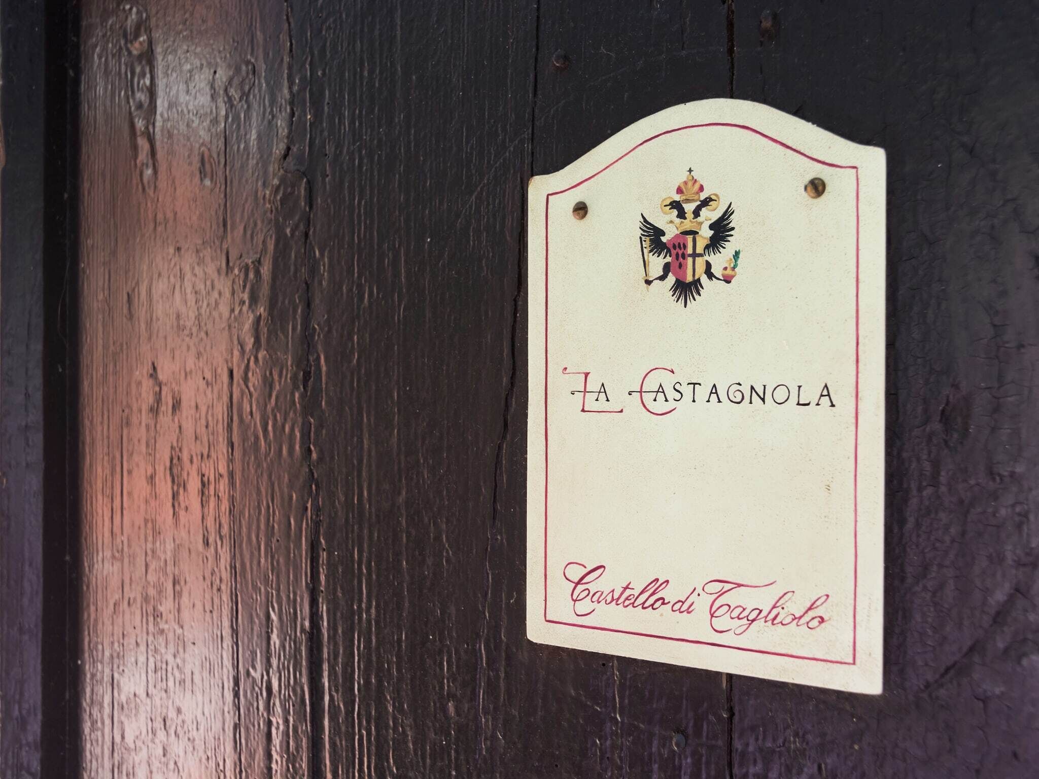 Une enseigne en bois ornée d’un blason et portant l’inscription « LA CASTAGNOLA Castello di Eghidio ».