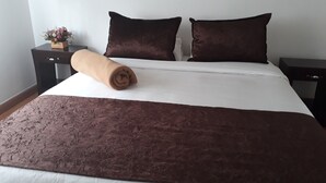 Un lit bien fait, avec une couverture marron, deux oreillers marrons et une serviette enroulée posée sur le côté.