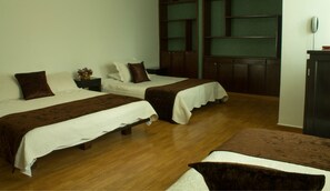A hotel room with two single beds, a wooden desk, a telephone, and a green-framed window. - Eco Boutique Hotel Torre II (Bogotá)