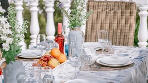 A table set for a meal with plates, glasses, a bottle, and a fruit bowl. - Villa in Cala Llonga near Beach & Ferry Port (Cala Llonga (santa Eulalia del Rio))