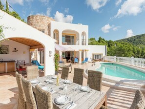 A two-story villa with a pool, outdoor dining area, and a stone wall. - Villa in Cala Llonga near Beach & Ferry Port (Cala Llonga (santa Eulalia del Rio))