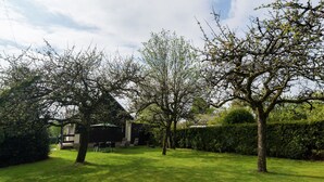 A well-maintained garden with a wooden house, neatly trimmed grass, and mature trees.