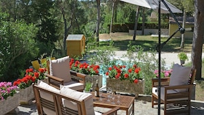 Une terrasse extérieure avec des meubles en bois, une table avec des verres à vin et un grand parasol pour faire de l’ombre.