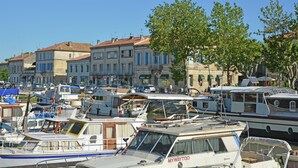 Un port de plaisance où sont amarrés différents types de bateaux, entouré de bâtiments de style européen traditionnel.