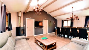 A spacious living area with a sofa, a coffee table, and a dining table with chairs. - Luxurious Chalet in Beauraing with Sauna (Beauraing)