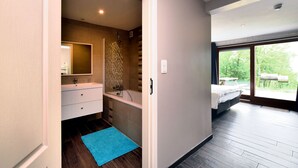 A modern bathroom with a shower, a bathtub, and a vanity. There is a blue rug on the floor. - Luxurious Chalet in Beauraing with Sauna (Beauraing)