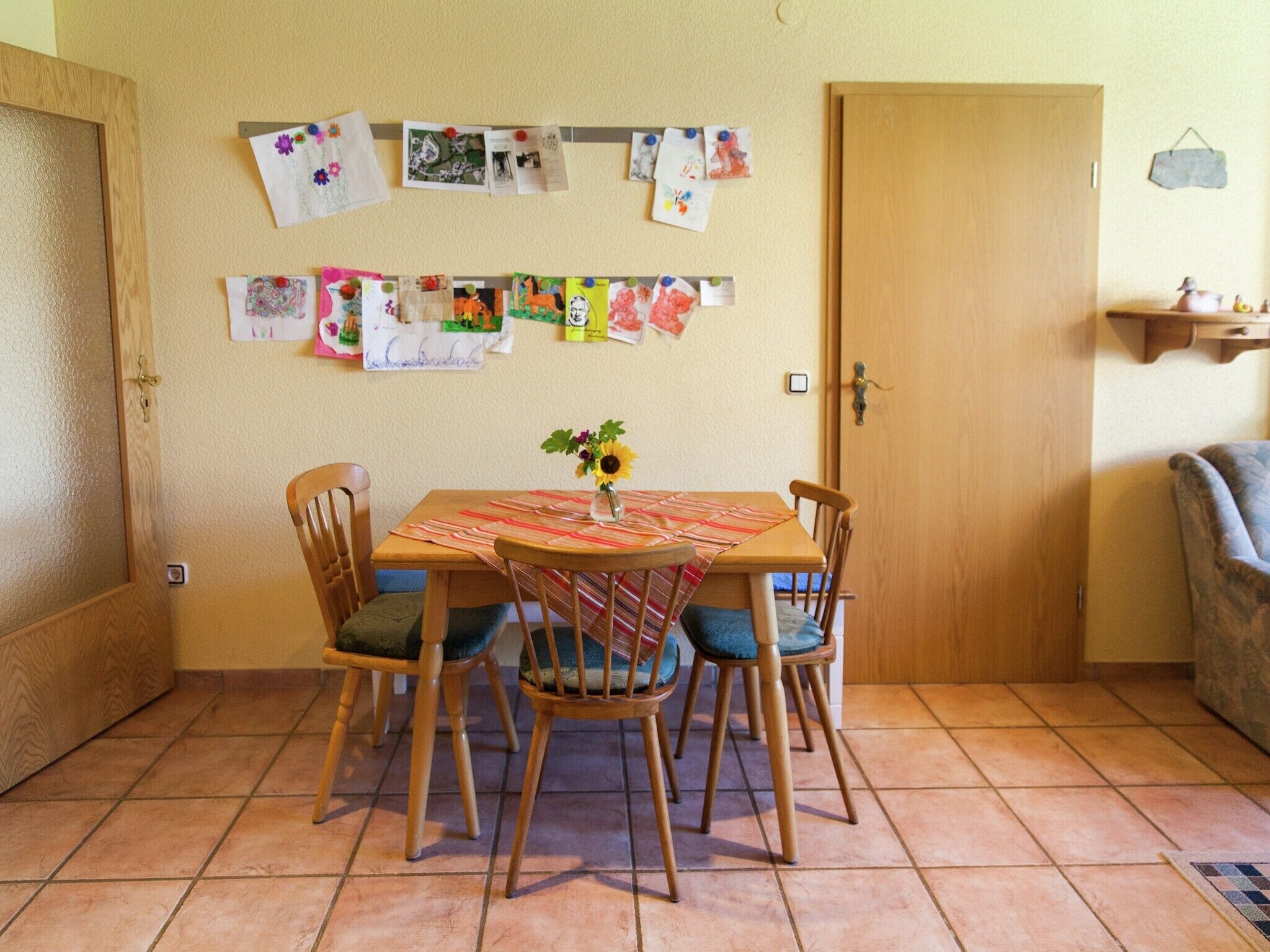 Un coin repas avec une table en bois, quatre chaises et un vase rempli de tournesols.