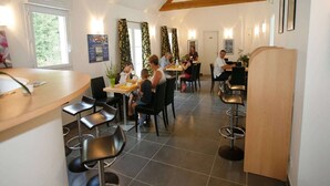 Ein Restaurant mit mehreren Tischen und Stühlen, einer Holzbalkendecke und einem Fliesenboden.