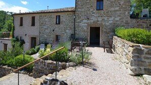 A stone building with a courtyard, outdoor seating, and a gravel path. - Countryside cottage in Pergola (Pergola)