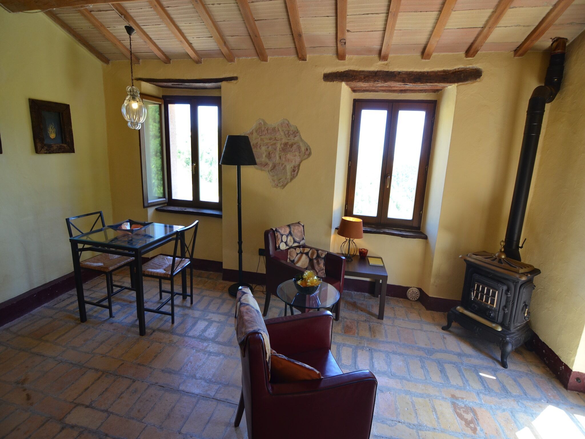 A cozy living room with a wooden ceiling, a fireplace, a dining table with chairs, and a sofa.