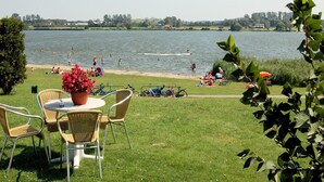Vista del lago con zona de comedor que incluye sillas de mimbre y una mesa con un centro de mesa floral.