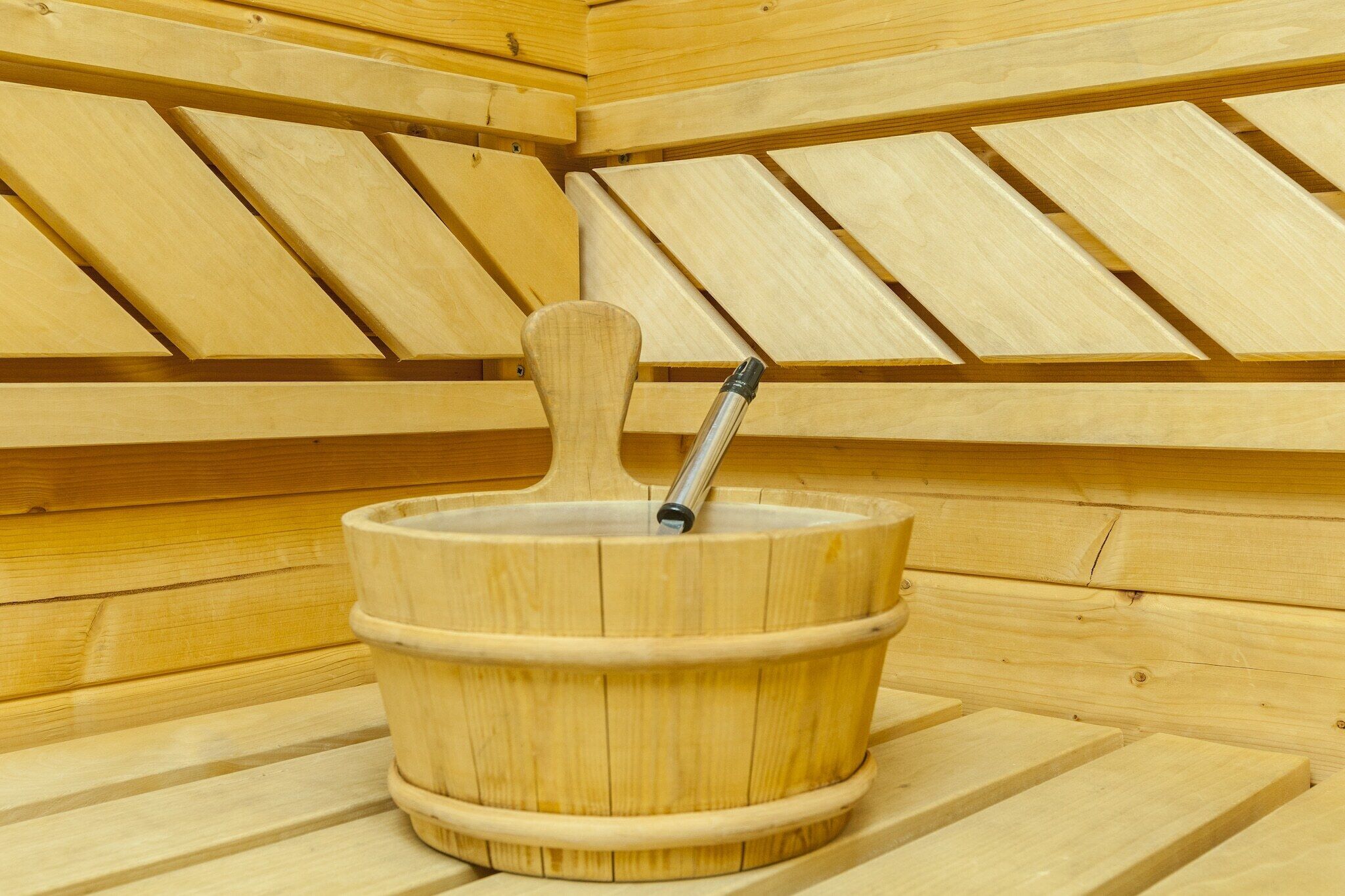 Una sauna de madera con un balde de madera y un asa de metal.