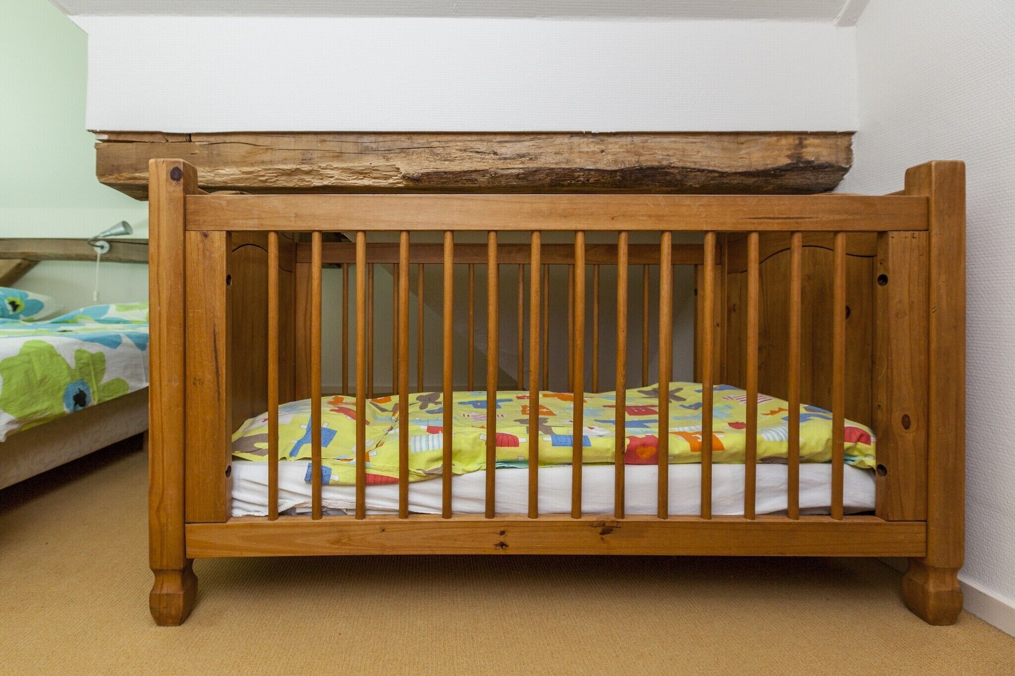 A wooden crib with a mattress and a colorful blanket.