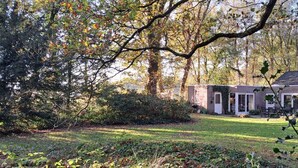 A small house with a brick exterior, surrounded by trees and a grassy yard. - Villa in Vessem near Eindhoven (Vessem)