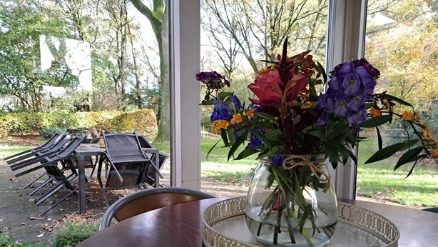 A dining table with a vase of flowers and a decorative tray. - Villa in Vessem near Eindhoven (Vessem)