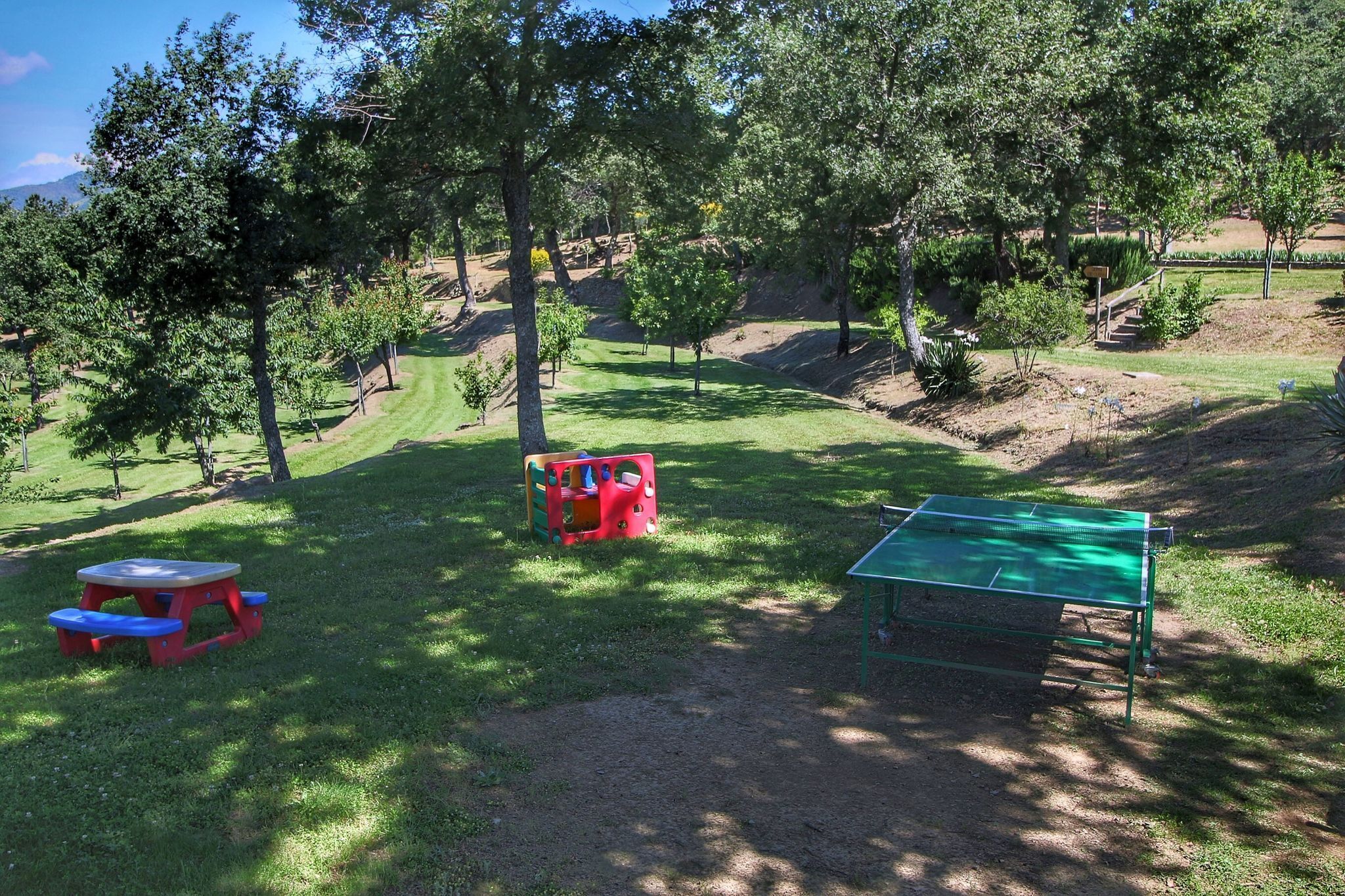 Ein Park mit Picknicktischen, einem Spielplatz und einem Tennisplatz.