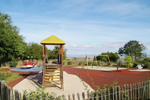 Ein Spielplatz mit Klettergerüst, Schaukeln und einer Rutsche.