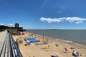 Ein Strand mit einer burgähnlichen Struktur, sandigem Ufer und blauem Himmel.