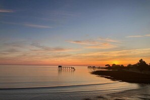 Un paysage paisible au bord de l’eau, au coucher du soleil, avec une jetée qui s’avance dans l’eau.