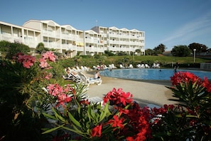 Ein Hotel mit Poolbereich, mehreren Balkonen und üppiger Bepflanzung.