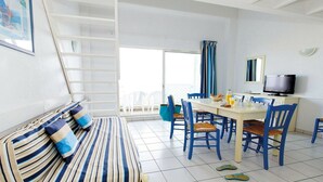 A room with a bed, a dining table with chairs, a television, and a window with curtains. - Apartment with sea or pool views (Fouras)