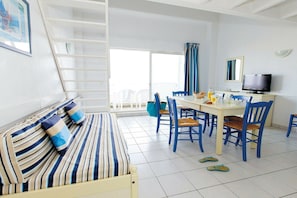 Ein Zimmer mit einem Bett, einem Esstisch mit Stühlen, einem Fernseher und einem Fenster mit Vorhängen.