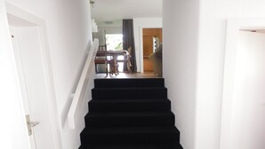 Eine Treppe mit schwarzen Teppichstufen, die zu einer Zwischenebene führt.