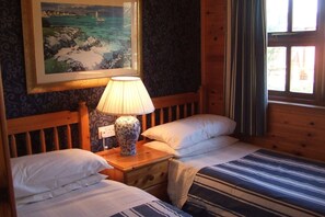 Restful retreat with two single beds, a nightstand, and a window offering a view of the outdoors.
