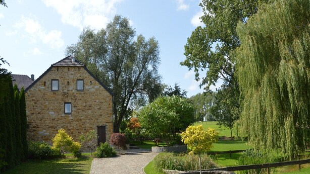 A stone building with a tiled roof, surrounded by a well-maintained garden with a cobblestone path leading to the entrance. - Luxury Holiday Haven in Sprimont (Sprimont)