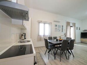 A modern kitchen with a built-in stove, a sink, and a dining area with a table and chairs.