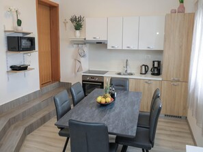 A modern kitchen with white cabinets, a microwave, a stove, and a coffee maker.