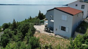 A two-story building with a red-tiled roof, a pool, and a view of a large body of water. - Luxury Apartment with heated pool in Starigrad (Starigrad)