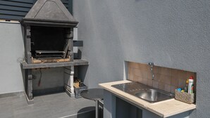 An outdoor kitchen with a built-in grill and a sink. - Luxury Apartment with heated pool in Starigrad (Starigrad)
