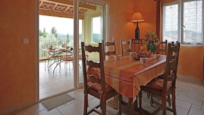 Un comedor con una mesa preparada para cuatro personas, sillas de madera, una lámpara y vistas al exterior.