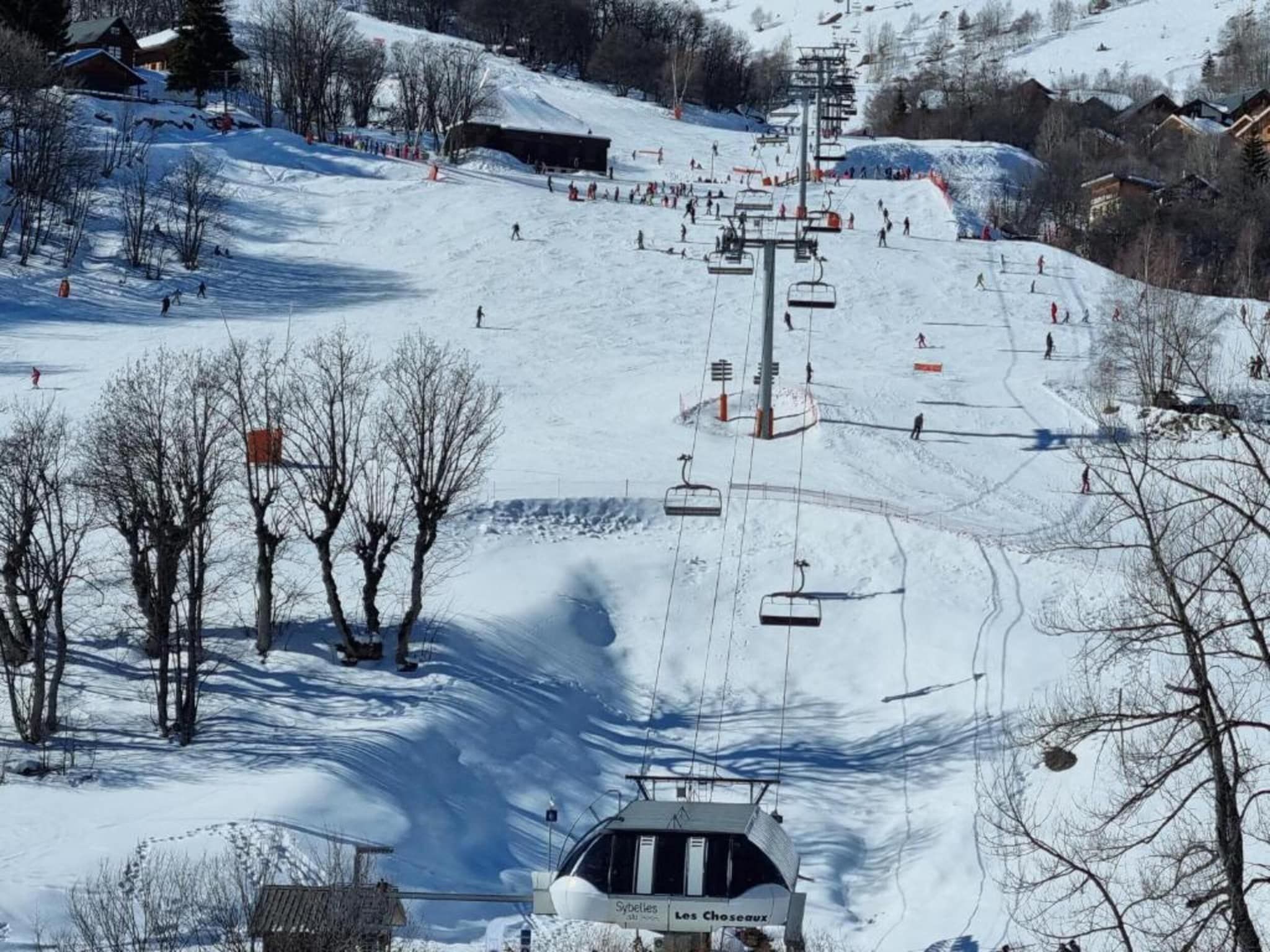 A ski resort with a chairlift, snow-covered slopes, and buildings in the background.