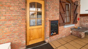 A brick building with a wooden door and a chalkboard sign.