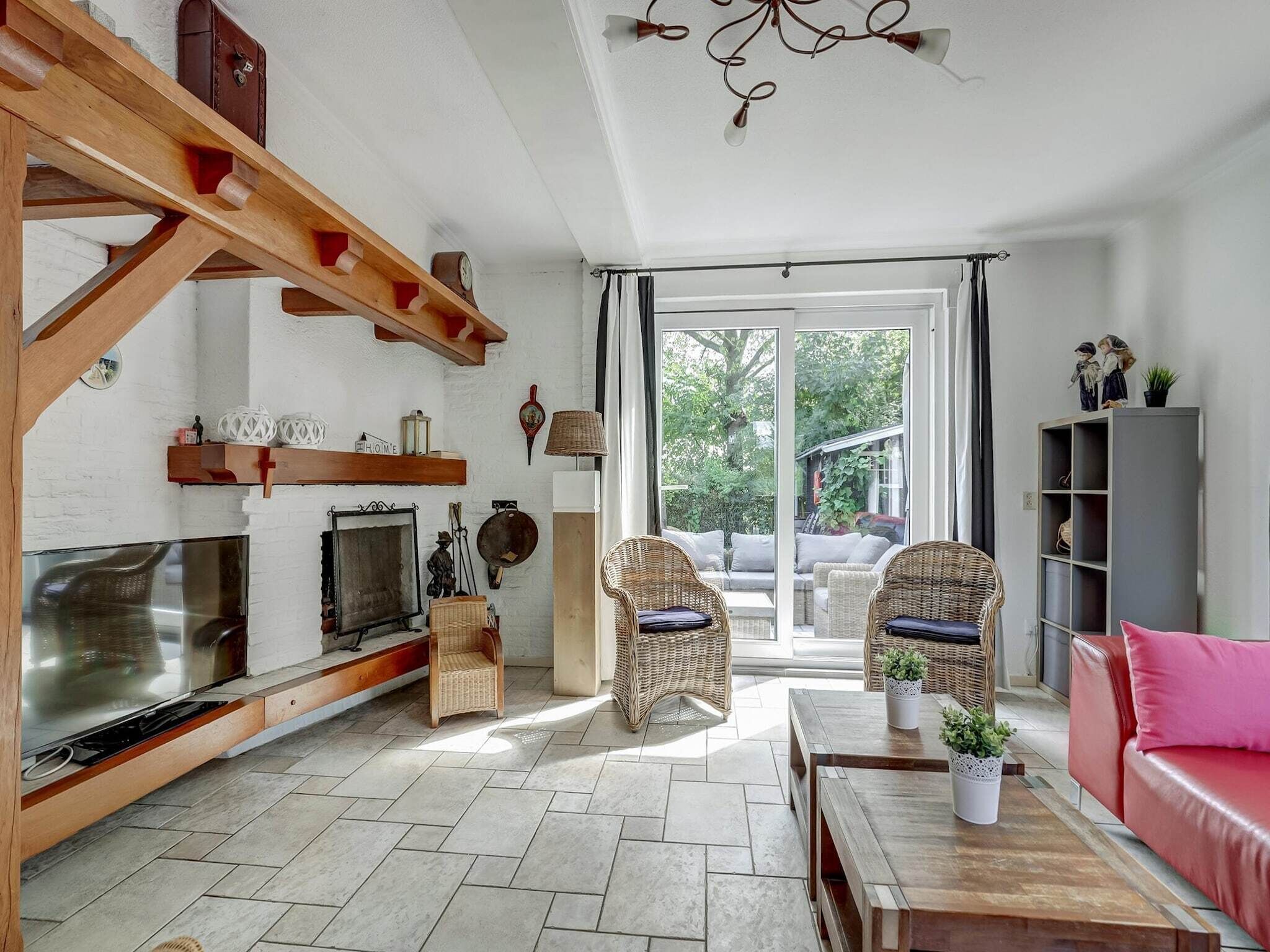 Un amplio salón con chimenea, muebles de mimbre, televisor y un ventanal grande.
