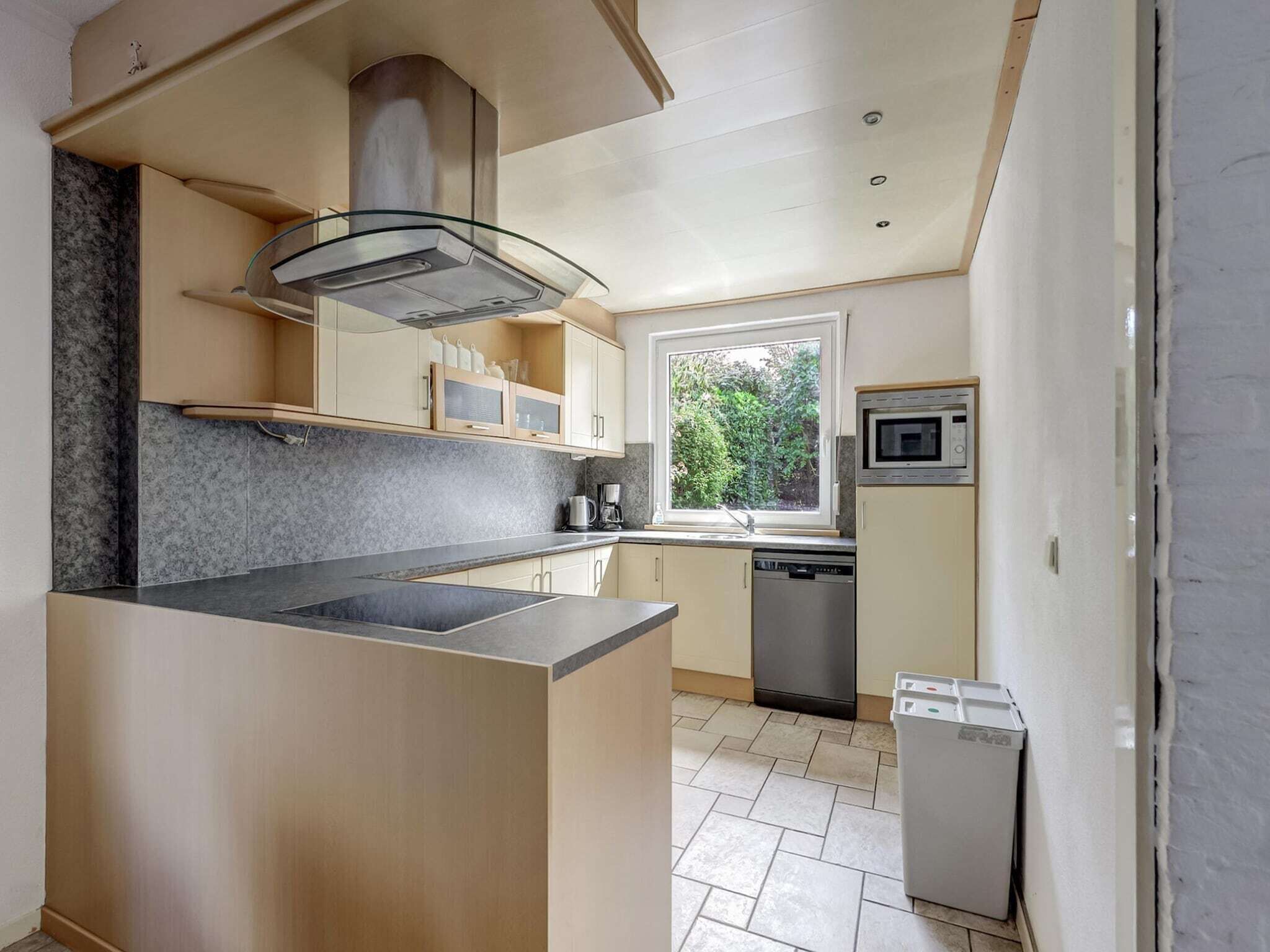 Een moderne keuken met een centraal eiland, geïntegreerde apparatuur en uitzicht op groen.