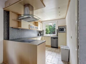 Una cucina moderna con isola centrale, elettrodomestici integrati e vista su una zona verde.