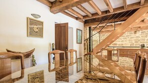Quarto com mesa de vidro que reflete a decoração, escada de madeira e paredes de pedra.