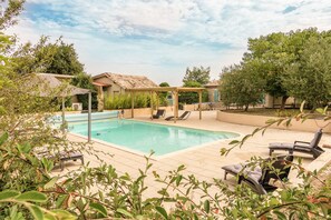 Uma área de piscina com espreguiçadeiras e um pérgola.