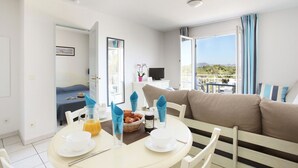 A hotel room with a dining area, a bed, a TV, and a balcony with a view. - Spacious Apt Near the Beach (Saint-Aygulf)