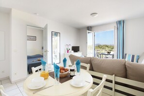 Quarto de hotel com área de refeições, cama, televisão e varanda com vista.