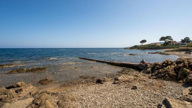 A rocky shoreline with clear water, a wooden jetty, and a person fishing. - Spacious Apt Near the Beach (Saint-Aygulf)